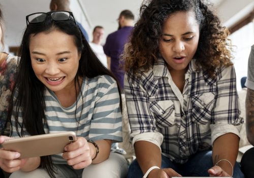 Freunde spielen gemeinsam auf ihren Smartphones.
