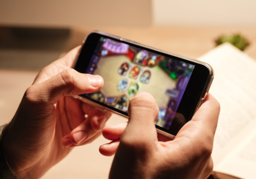 Hände halten ein Smartphone, auf dem ein Game geöffnet ist