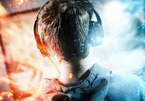 Junge mit Headset sitzt vor dem Monitor und lässt sich in den Bann ziehen