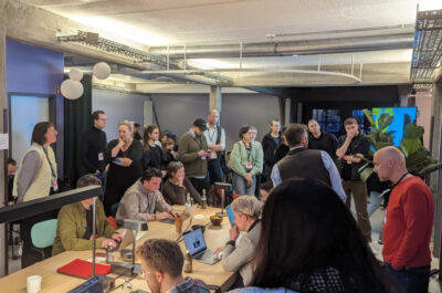 Besucher des KI-Themenfestivals stehen um die Teilnehmer des Prompt Battles herum und beobachten gespannt ihre Arbeit.
