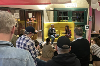 Mehrere Besucher sitzen um eine Bühne im SPACE Hamburg. Zwei Personen sind dort auf einem gemütlichen Sofa im Talk.